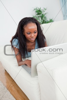 Woman lying on the sofa working with her laptop