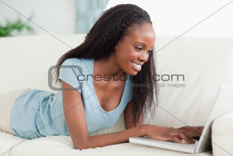 Woman lying on the couch working with her laptop
