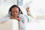 Woman with eyes closed enjoying music on her couch