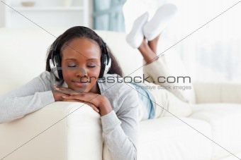 Woman with eyes closed enjoying music on her couch