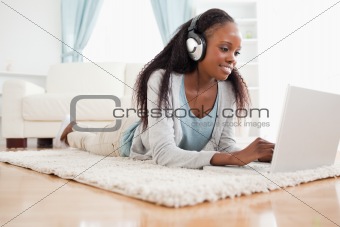 Woman lying on the floor with her laptop enjoying music
