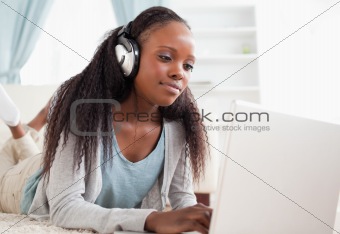 Close up of woman lying on the floor with her notebook enjoying music