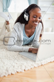 Close up of woman lying on floor with her laptop enjoying music