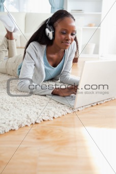 Close up of woman lying on floor with her notebook enjoying music