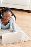 Close up of woman lying on floor with laptop listening to music