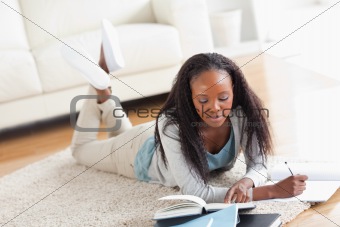Woman lying on carpet doing a book review