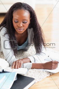 Close up of woman lying on the floor doing her homework