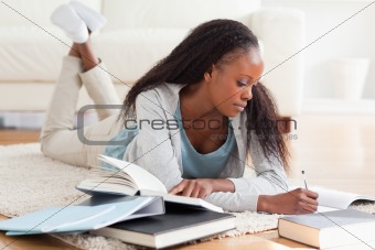 Woman lying on carpet working on book review