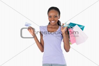 Happy woman with her shopping and credit card on white background