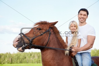 Little girl with her father on a horse