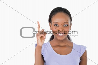Close up of smiling woman pointing upwards on white background