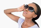 Close up of woman moving her sunglasses against a white background