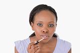 Close up of woman using lip gloss against a white background