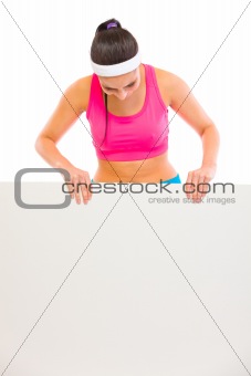 Fit woman in sportswear looking on blank billboard
