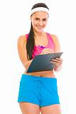 Smiling female fitness trainer writing in clipboard
