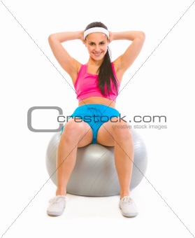 Smiling fit girl making abdominal crunch on fitness ball
