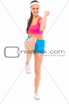 Full length portrait of smiling healthy girl in sportswear doing fitness excersice
