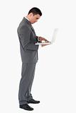Standing businessman typing on his laptop against a white background