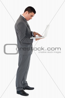 Standing businessman typing on his laptop against a white background