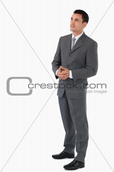 Businessman with hands folded looking upwards against a white background