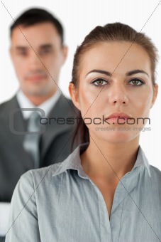 Close up of serious looking businesswoman with colleague behind her