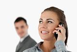Close up of smiling businesswoman on the phone with colleague behind her