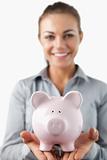 Close up of piggy bank being held by smiling female bank assistant