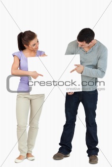 Young couple pointing and looking at sign they are holding