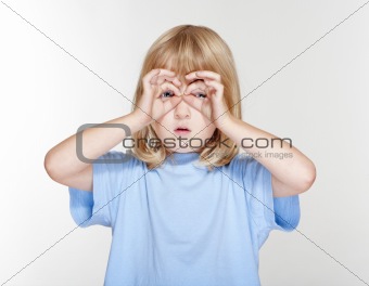 boy with long blond hair looking through fingers as binoculars - isolated on gray