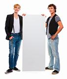 Two modern teenagers holding blank billboard. Isolated on white
