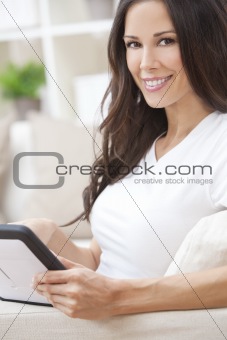 Young Brunette Woman Using Tablet Computer At Home on Sofa