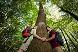 environmental conservation: young hikers embracing large tree