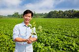 chinese farmer holding sapling and standing on his farm