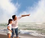 father pointing and little girl looking it on the beach