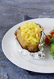 Baked potato filled with sour cream and  cheese, with salad