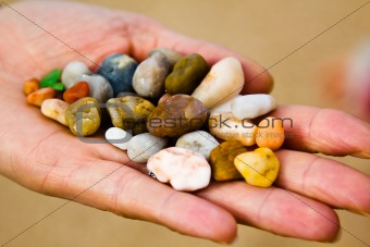 Small colorful stones in hand on sea coast