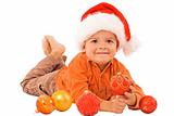 Boy in santa hat laying among christmas baubles - isolated