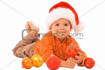 Boy in santa hat laying among christmas baubles - isolated