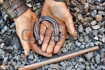 Detail of dirty hands holding horseshoe - blacksmith