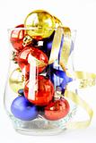 glass filled with colorful holiday ornaments and christmas decoration over white