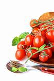 Fresh cherry tomatoes on plate, spoon and fork