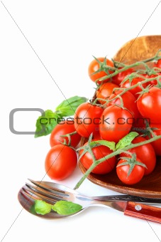 Fresh cherry tomatoes on plate, spoon and fork