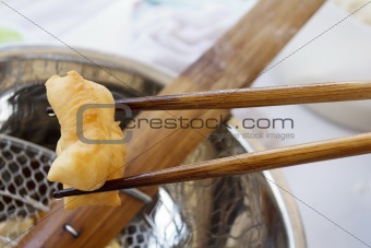Bamboo chopsticks holding deep-fried dough stick