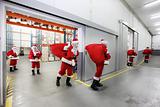 Santa clauses leaving a gift distribution center with red sacks