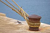 Rusty mooring bollard with ship ropes