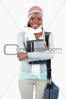 Smiling young student in winter clothes with her books