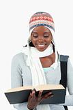 Close up of smiling student in winter clothes reading in her book