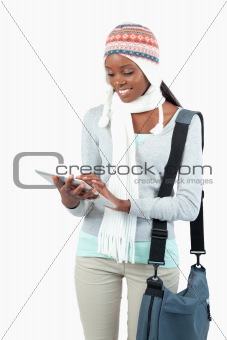 Smiling young woman in winter clothes using her tablet