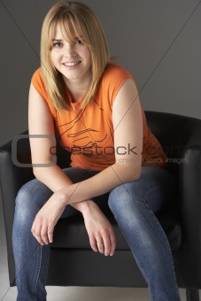 Studio Portrait Of Teenage Girl Sitting In Chair
