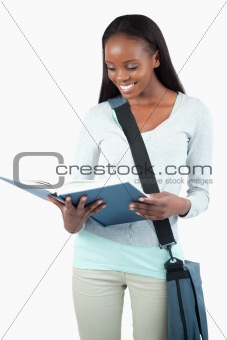 Smiling student with bag reading in her book